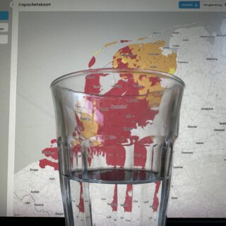 Half full / half empty glass of water in front of a grid capacity map of the Netherlands